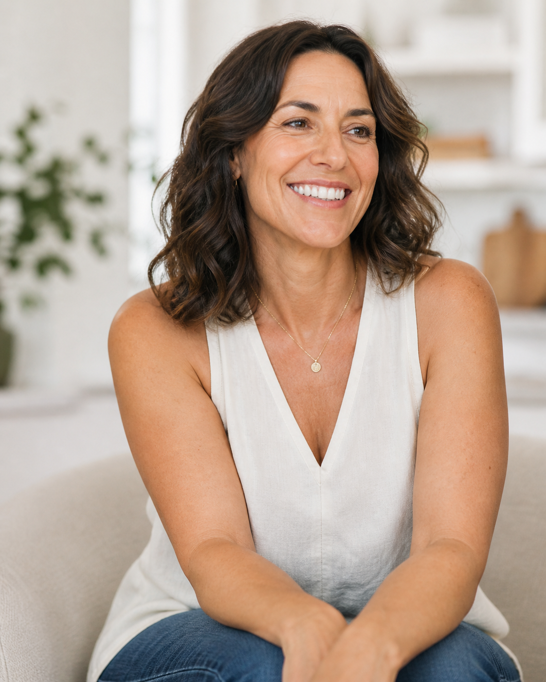 Midlife woman smiling brightly, seated at home in soft natural light
